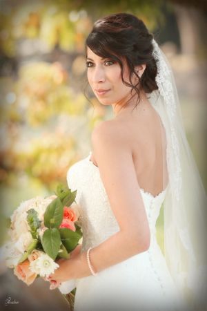 A bride with an elegant updo poses with her bouquet against a soft autumn background.