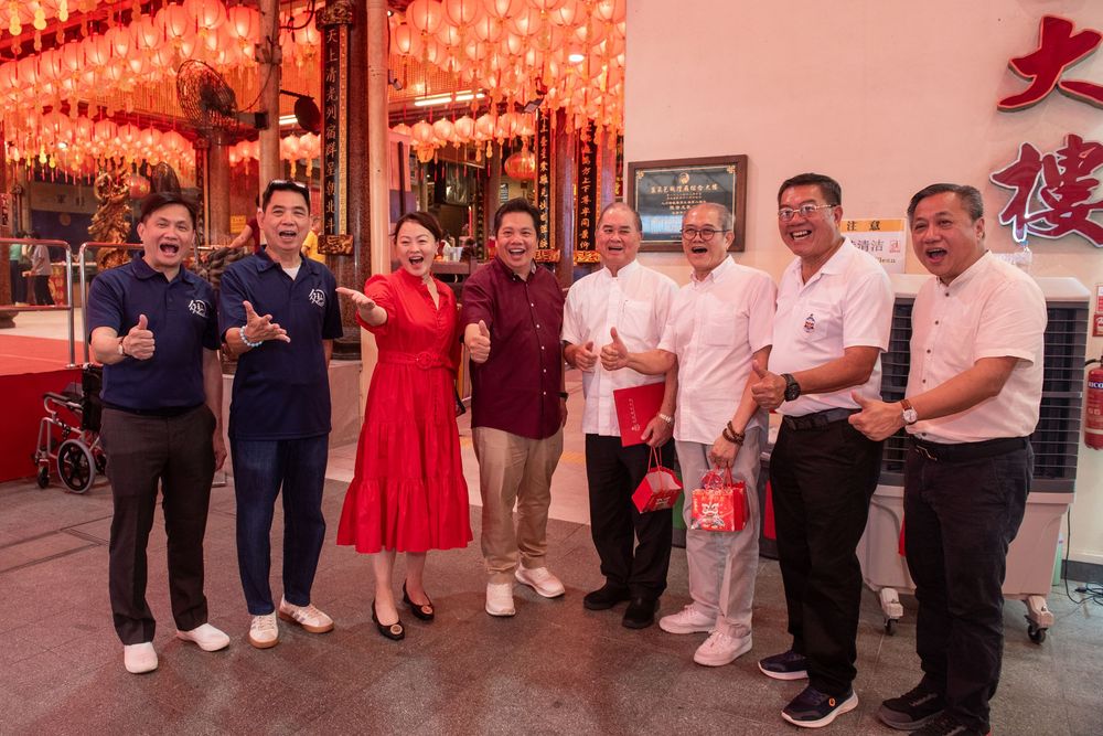 Group of people posing together outside a decorated Chinese building during a festive celebration.