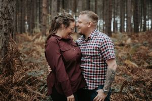 Casual couple shares intimate moment in autumn forest setting.