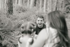 Black and white candid photo captures joy and laughter during family photoshoot.