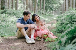 Family enjoys playful moment together on forest trail wearing coordinated outfits.