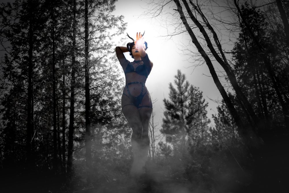 Image dramatique d’une femme avec des cornes devant un feu en pleine forêt