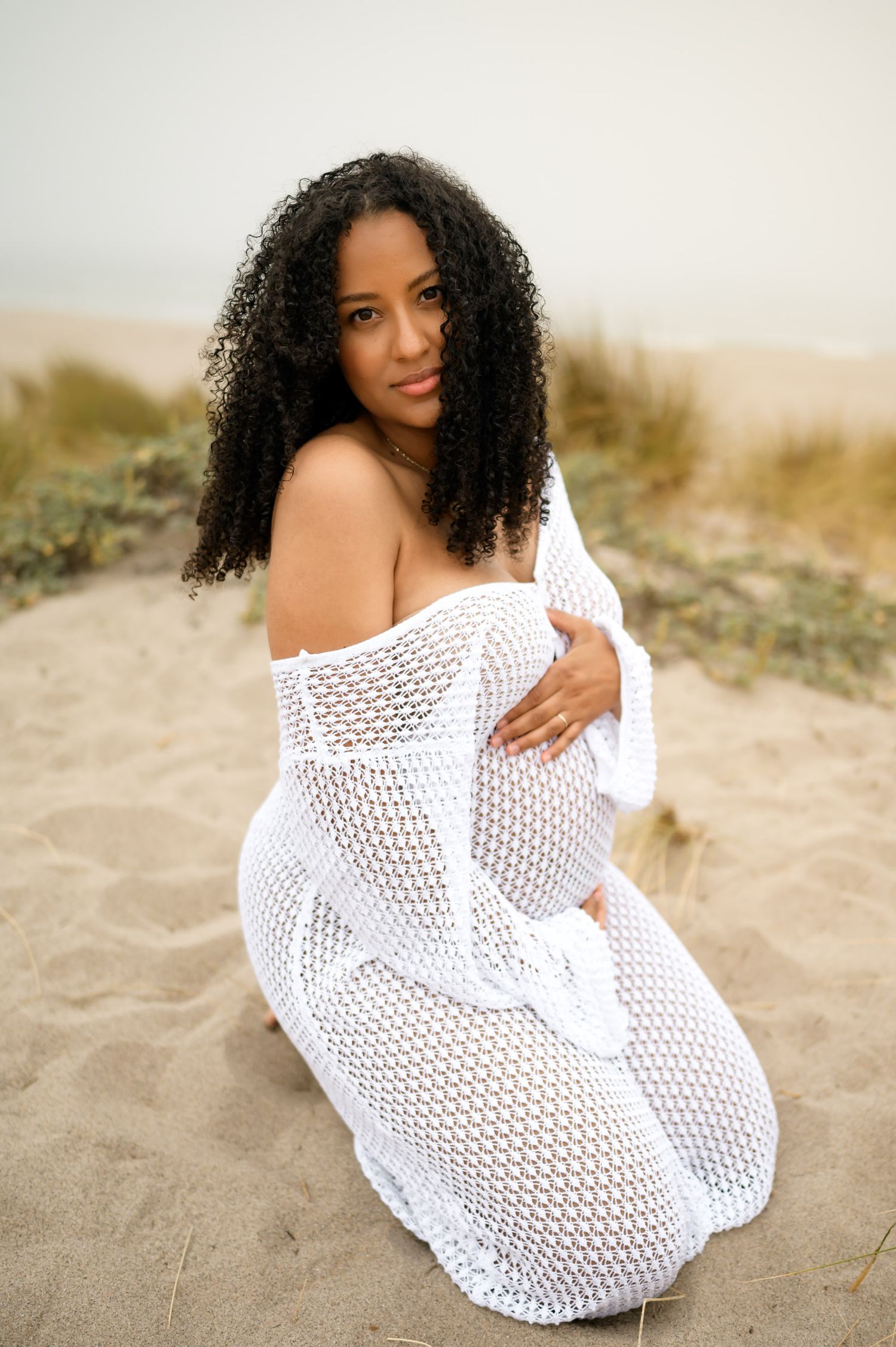 woman kneeling in sand during her Ventura beach maternity photoshoot by Santa Barbara maternity photographer