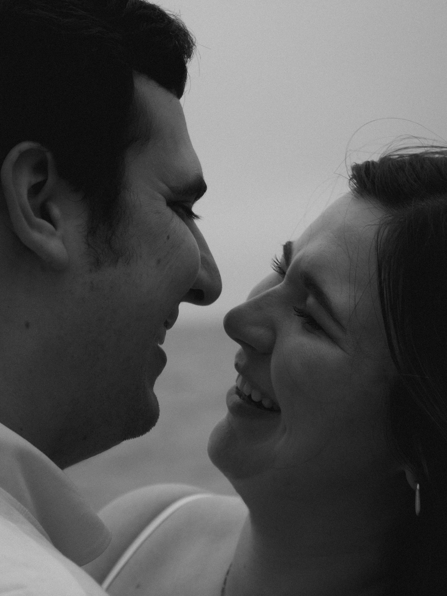 A black and white close-up portrait of a couple sharing a tender moment.