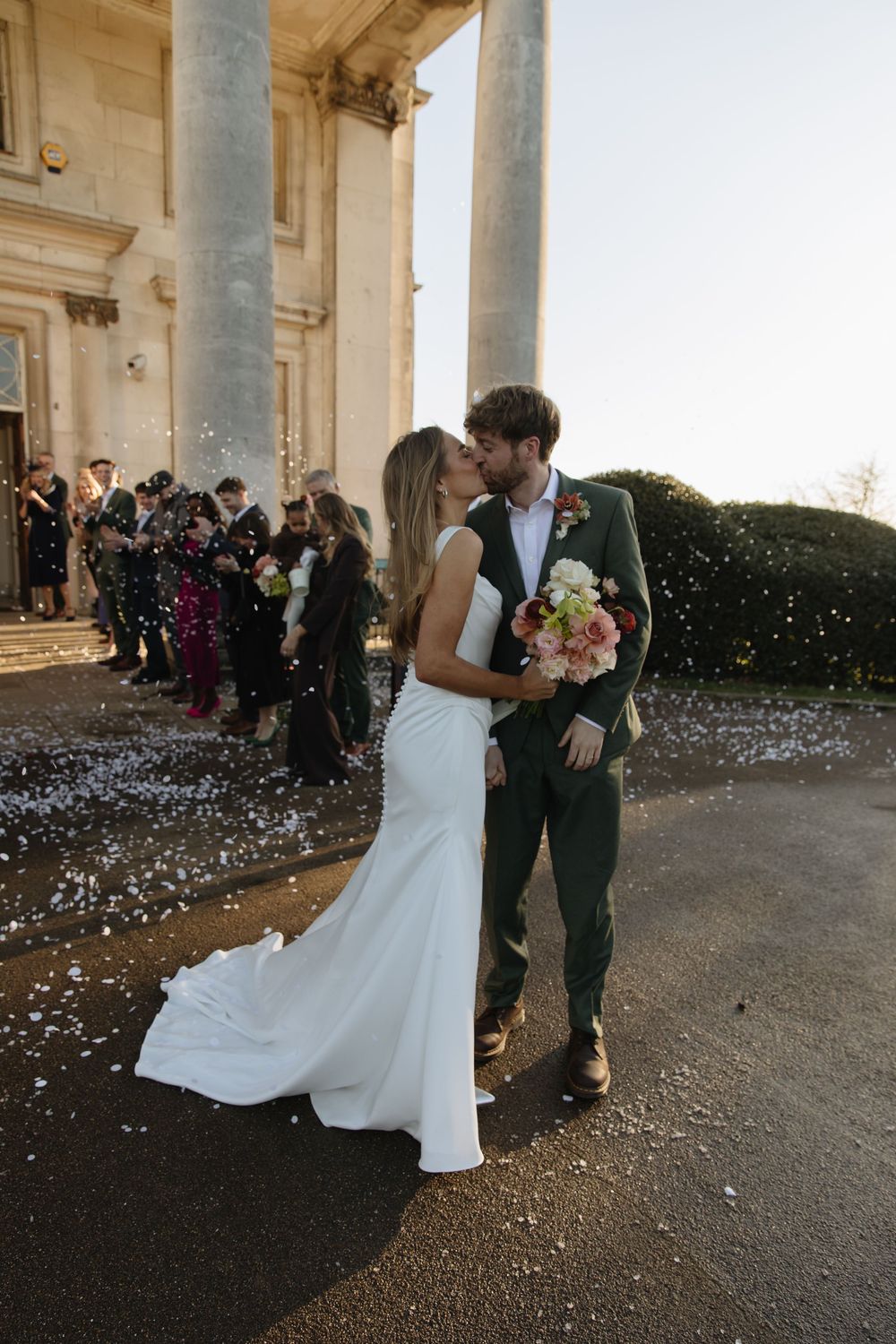 A couple shares a romantic moment during their wedding celebration as flower petals fall around them at an elegant venue.