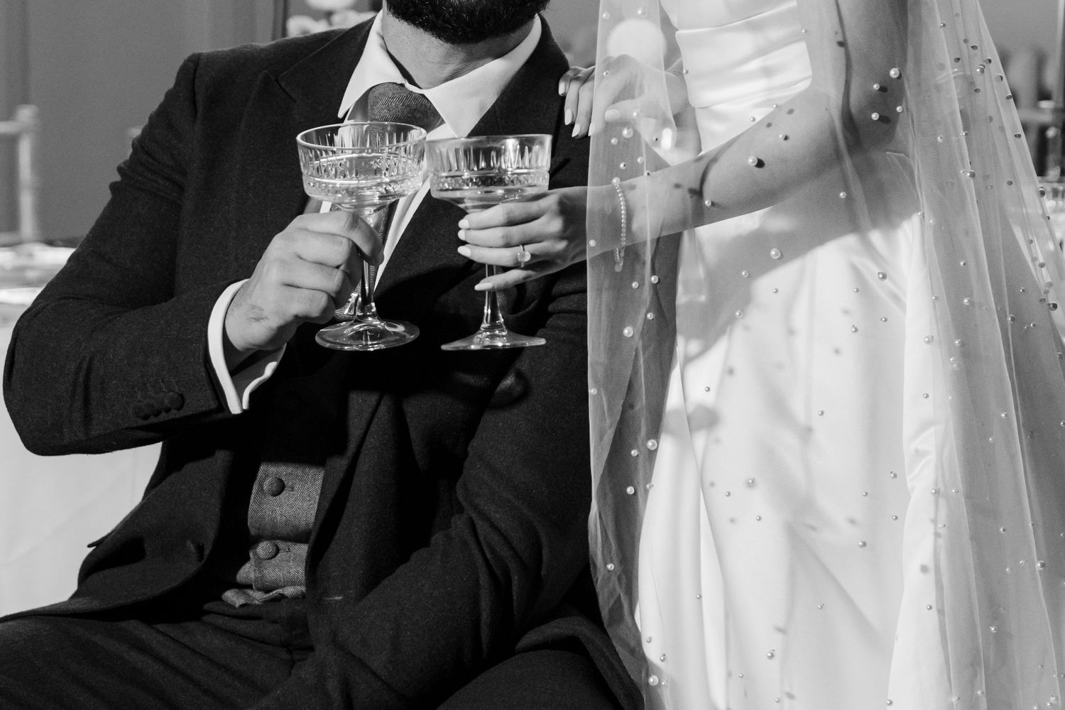 Black and white photo of newlyweds toasting with champagne glasses at their wedding celebration in county Fermanagh.