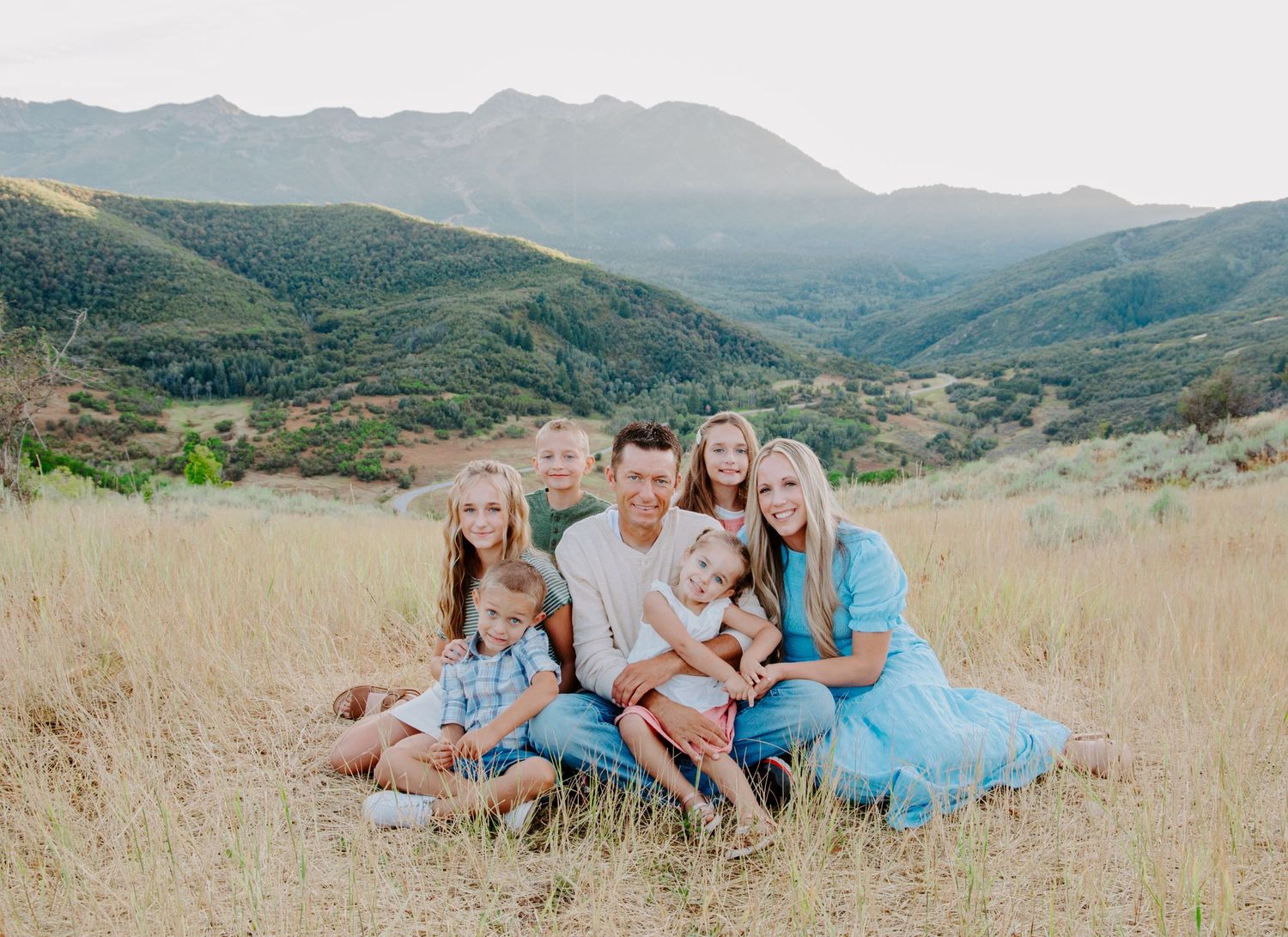 Family photography session in golden mountain field during sunset.