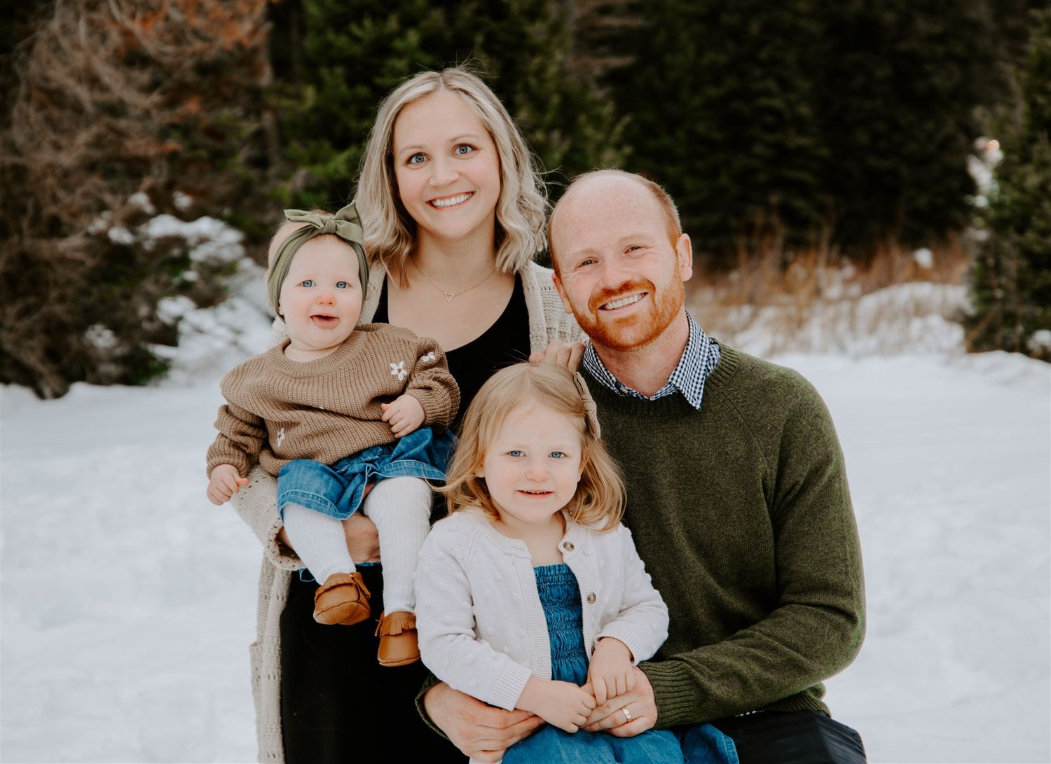 A winter portrait in the snow with evergreen trees in the background.