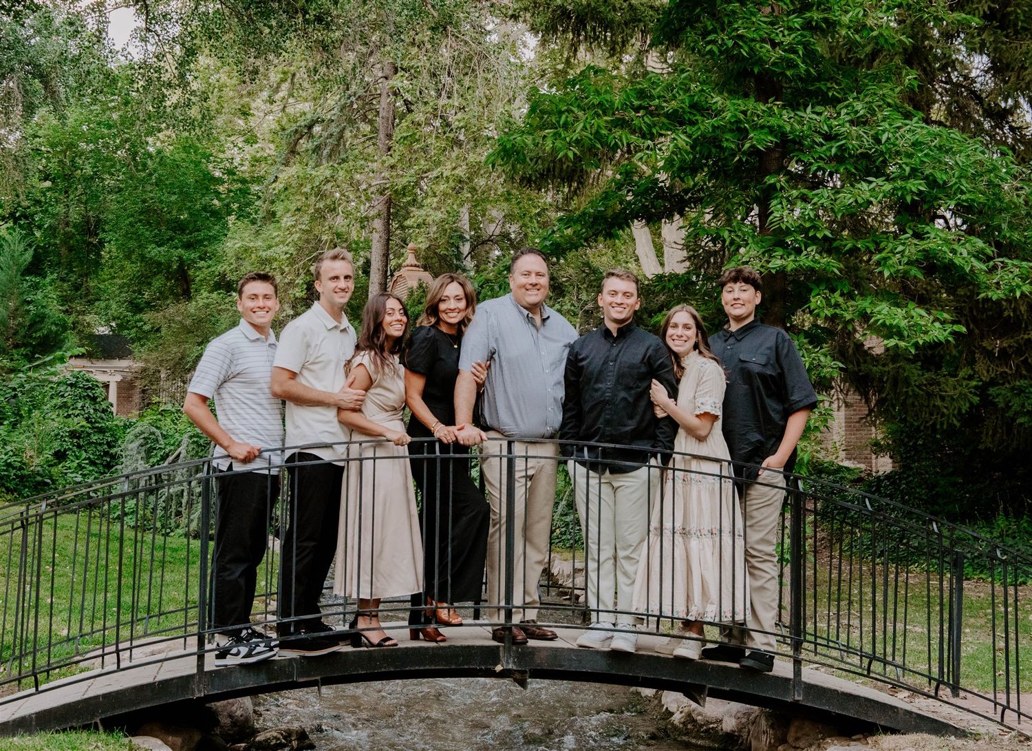 A group portrait on a stone bridge surrounded by lush green foliage.