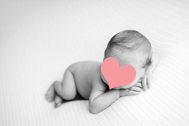 Artistic black and white portrait of baby on light backdrop.