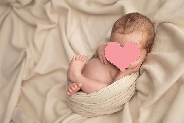 Sleeping newborn nestled in cozy cream wrap during studio photography session.