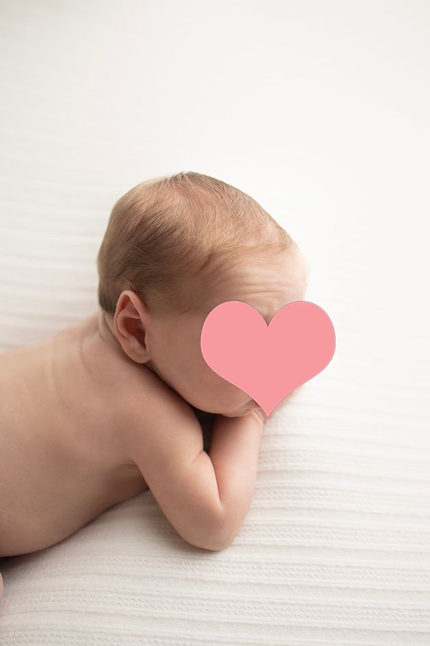 Artistic portrait of baby resting on white textured surface.