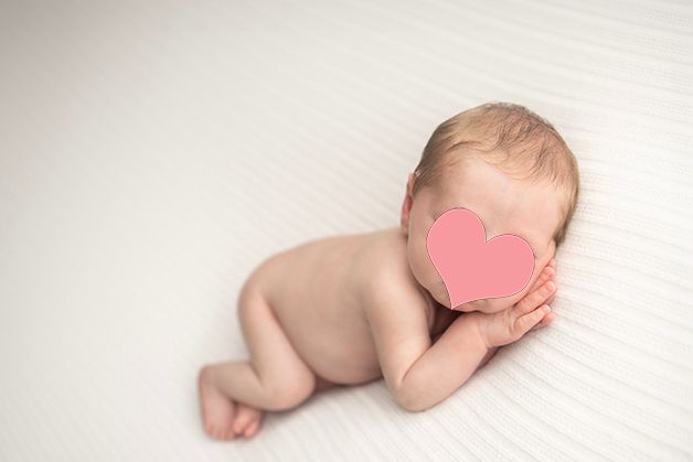 Peaceful baby resting in minimalist studio setting with white backdrop.