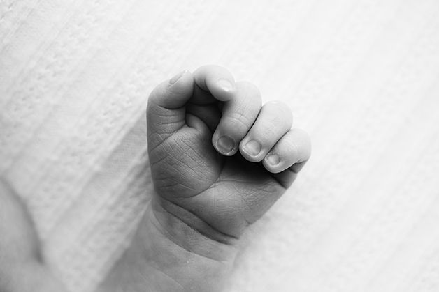 Close-up black and white photograph of tiny baby's clenched fist.