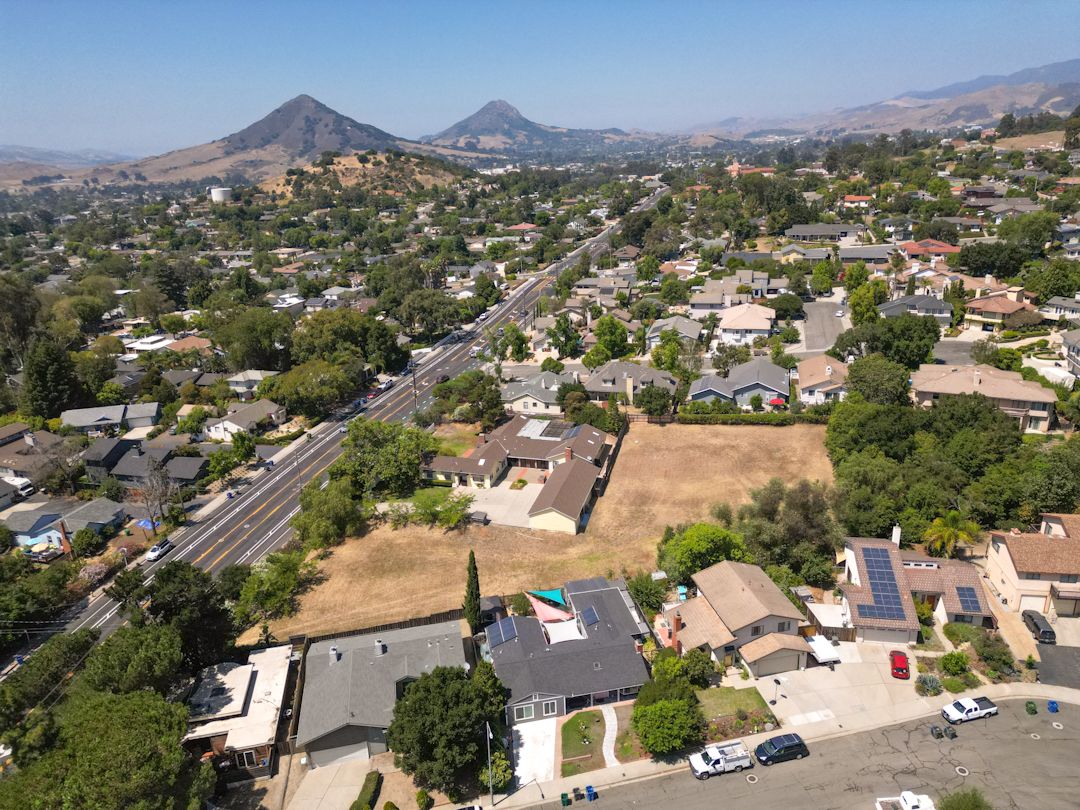 Aerial view of suburban neighborhood with mountains and hills in background.