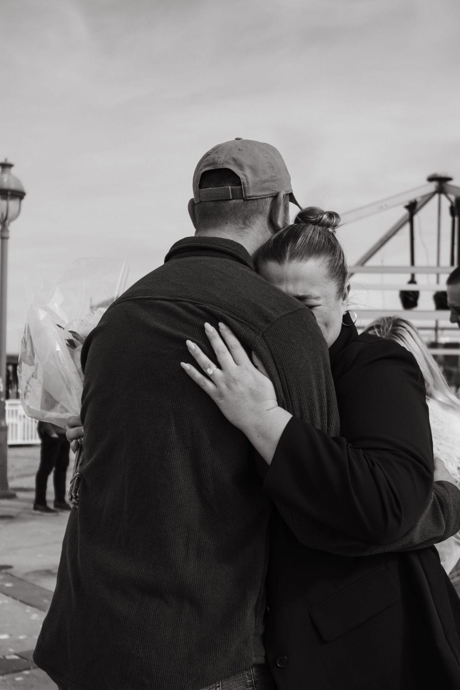 Intimate black and white moment of a couple embracing on a pier.