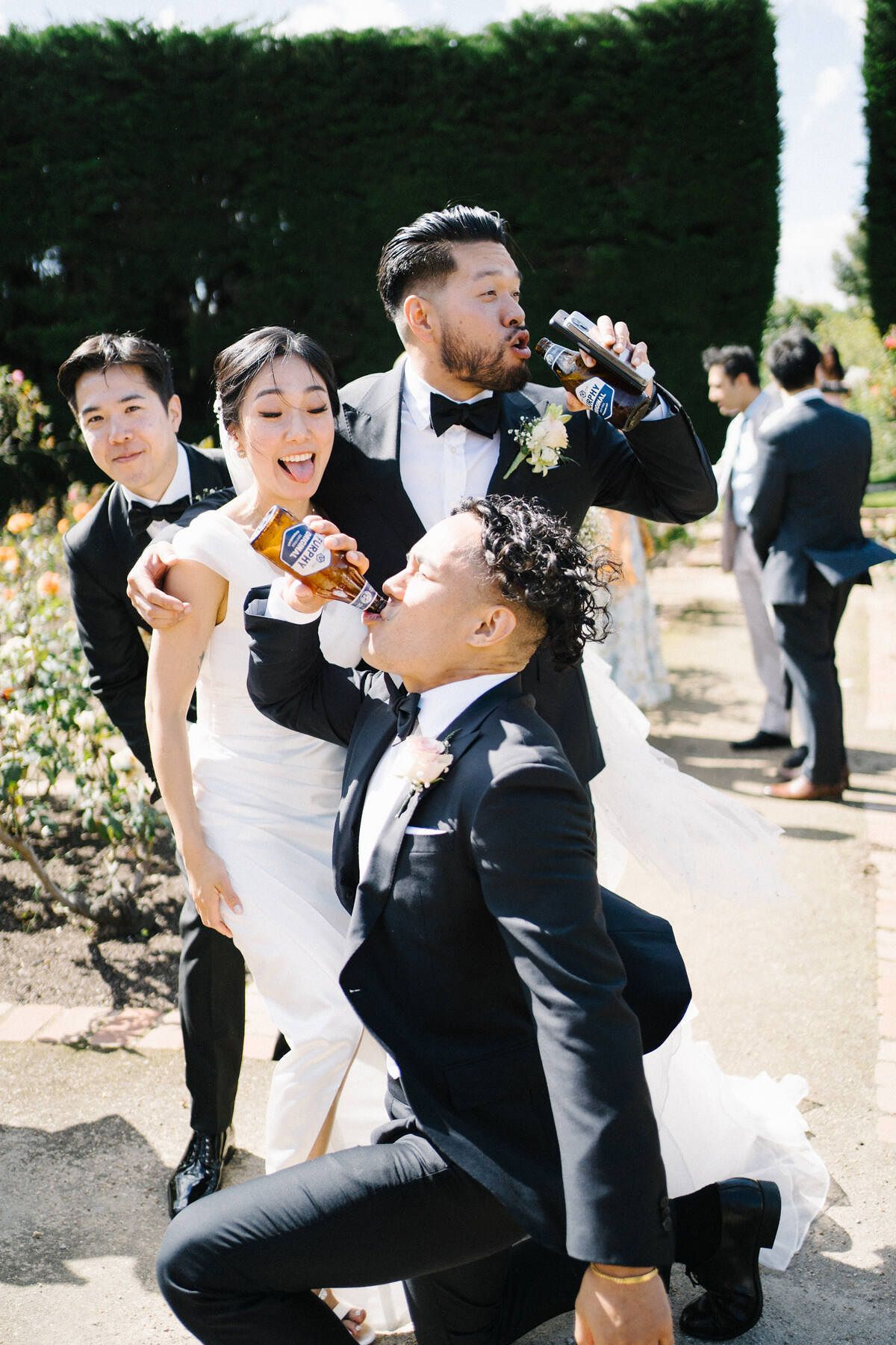 Sia and Duy with their best friends at the Botanic Gardens in St Kilda, Melbourne, throwing fun poses while holding beers after the ceremony