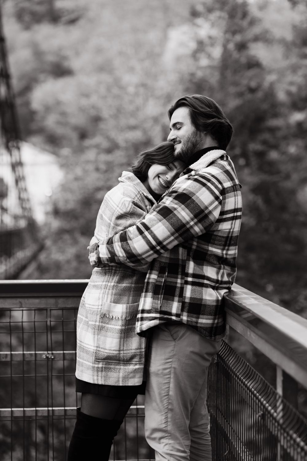 Tender black and white portrait of couple hugging on wooden deck in nature.