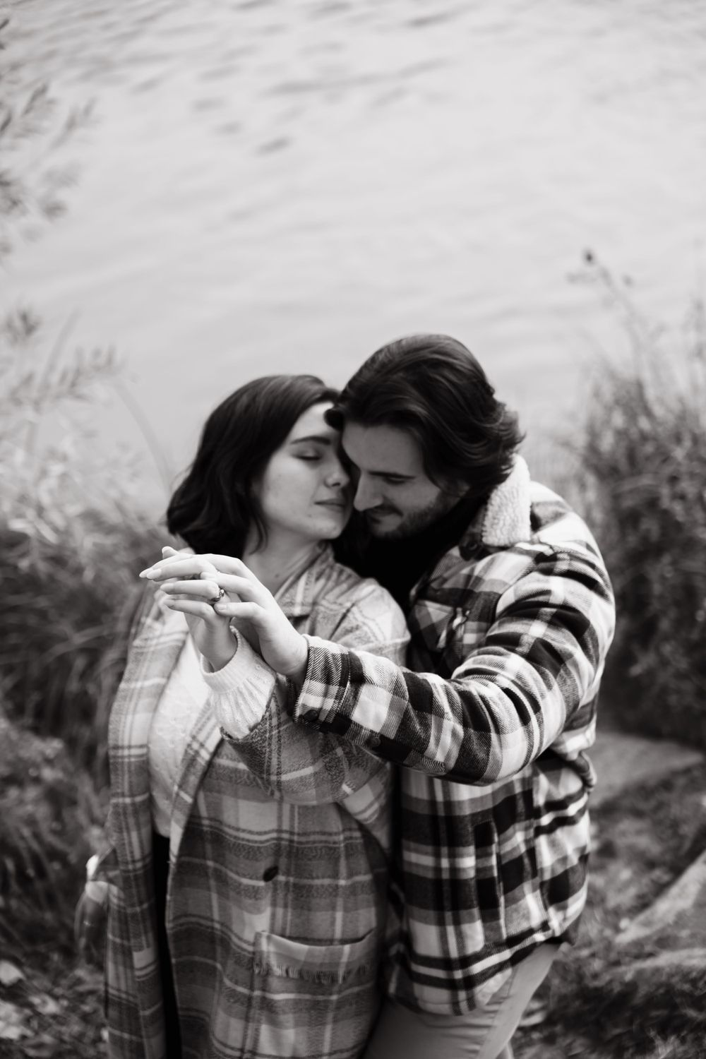 Intimate black and white portrait of a couple in plaid embracing outdoors.