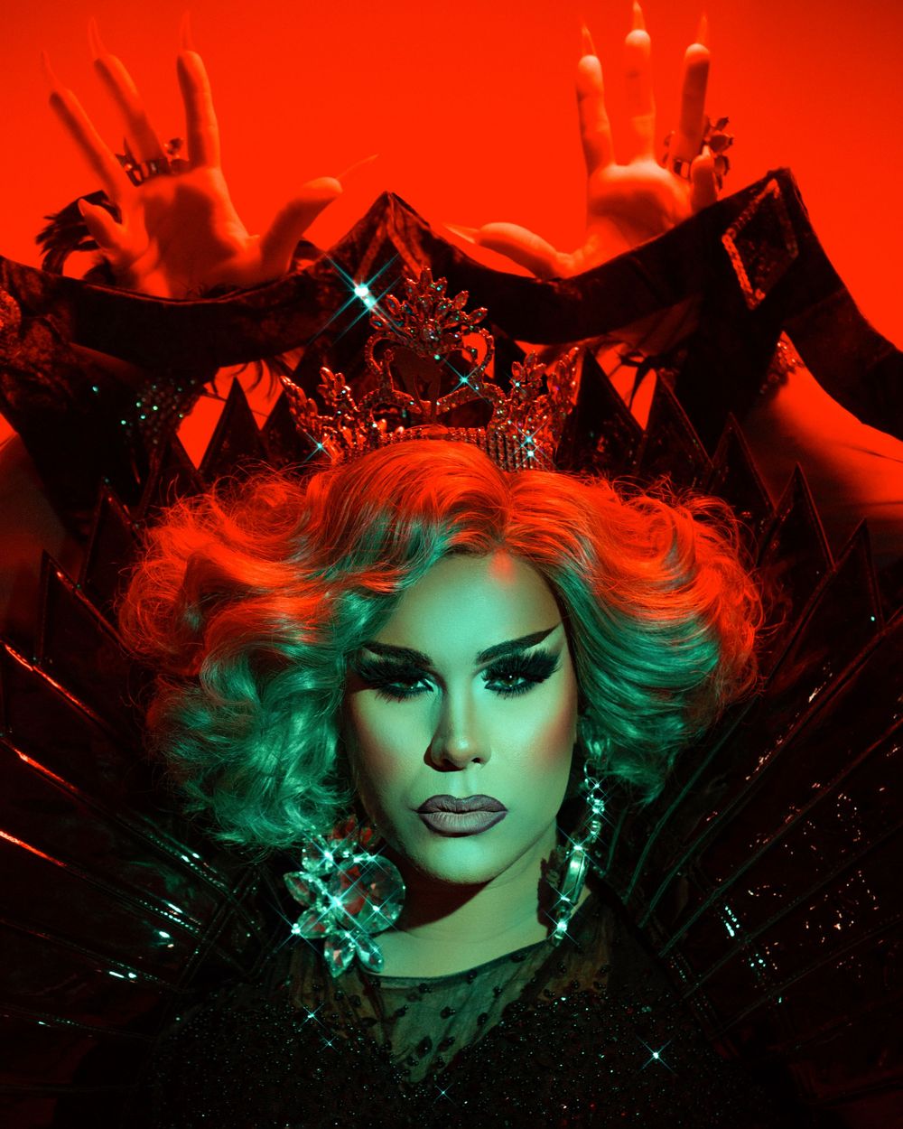 Artistic portrait shot in dramatic red and green lighting with sparkling accessories and expressive makeup.