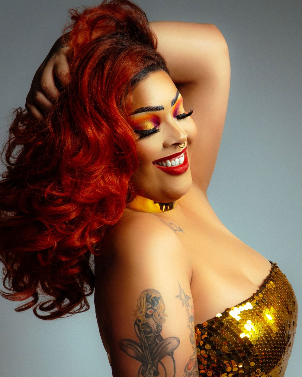 Glamour portrait with vibrant red hair, gold sequin outfit, and dramatic makeup.