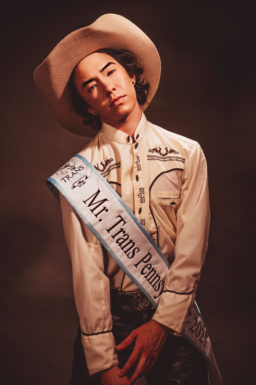 Moody fashion photography of person in western wear and sash posing against dark background in multiple artistic shots.