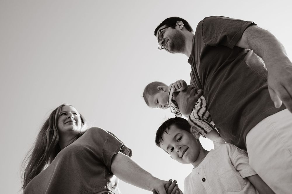 Black and white candid photo sequence showing someone helping another person up from the ground in a playful way.