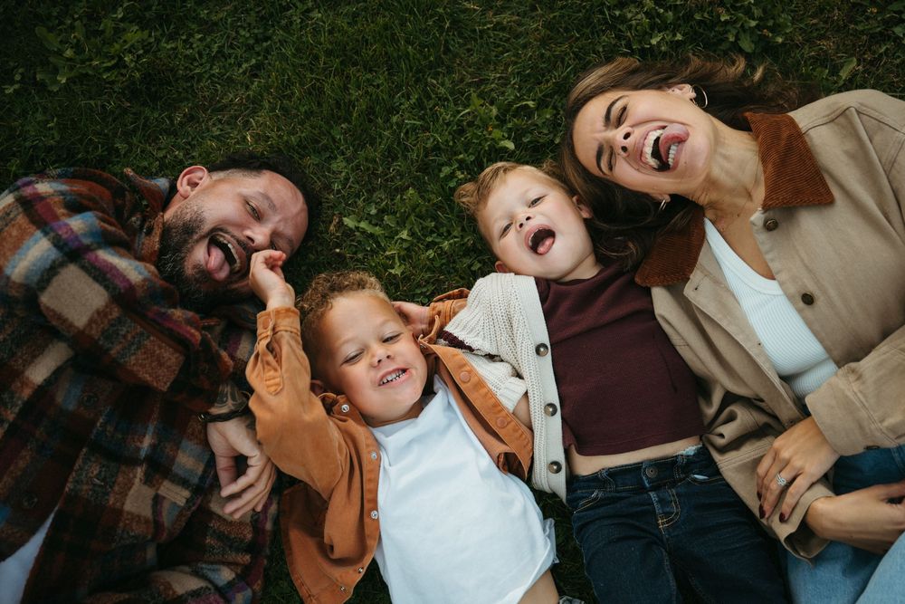 Family lying on grass sharing intimate moments in a series of candid outdoor photos.