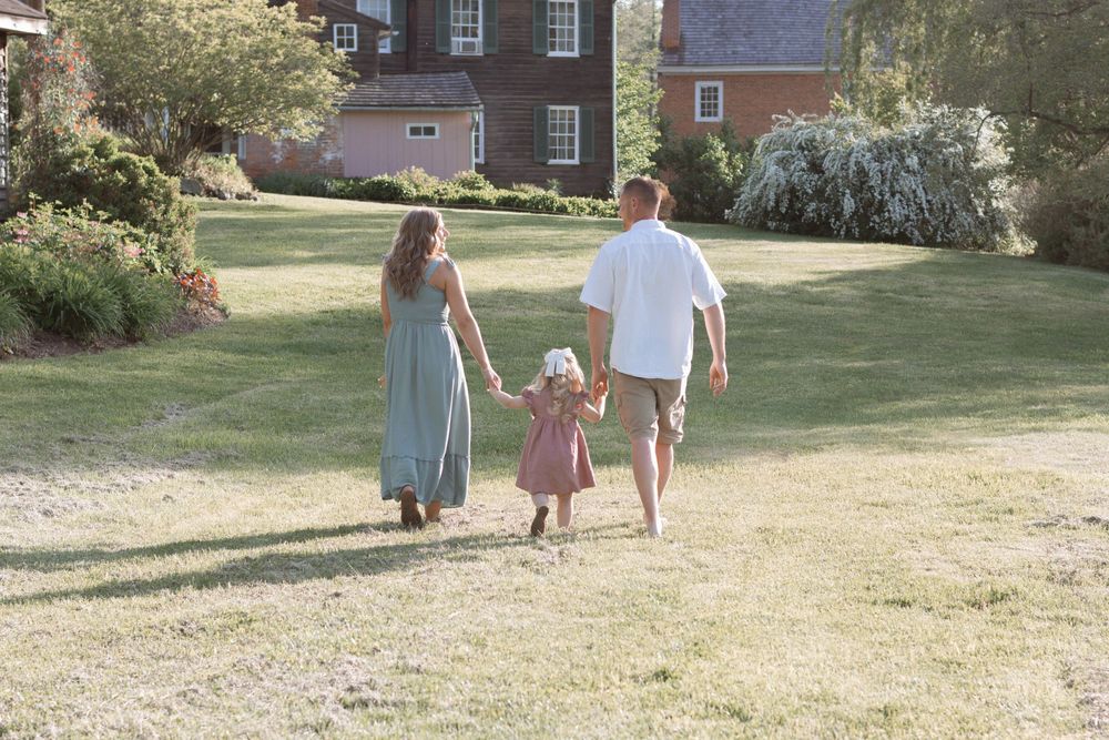 Family walking together on a grassy lawn with historic buildings in the background.