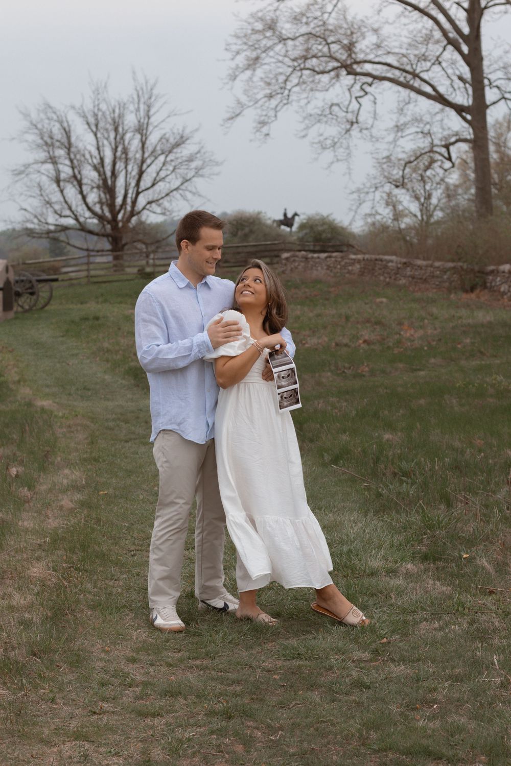 Couple shares joyful moment in countryside setting with rustic fencing.