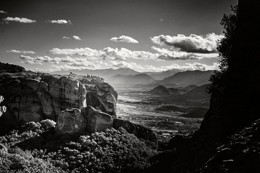 Black and white scenic vista of mountains and valleys stretching to the horizon under scattered clouds.