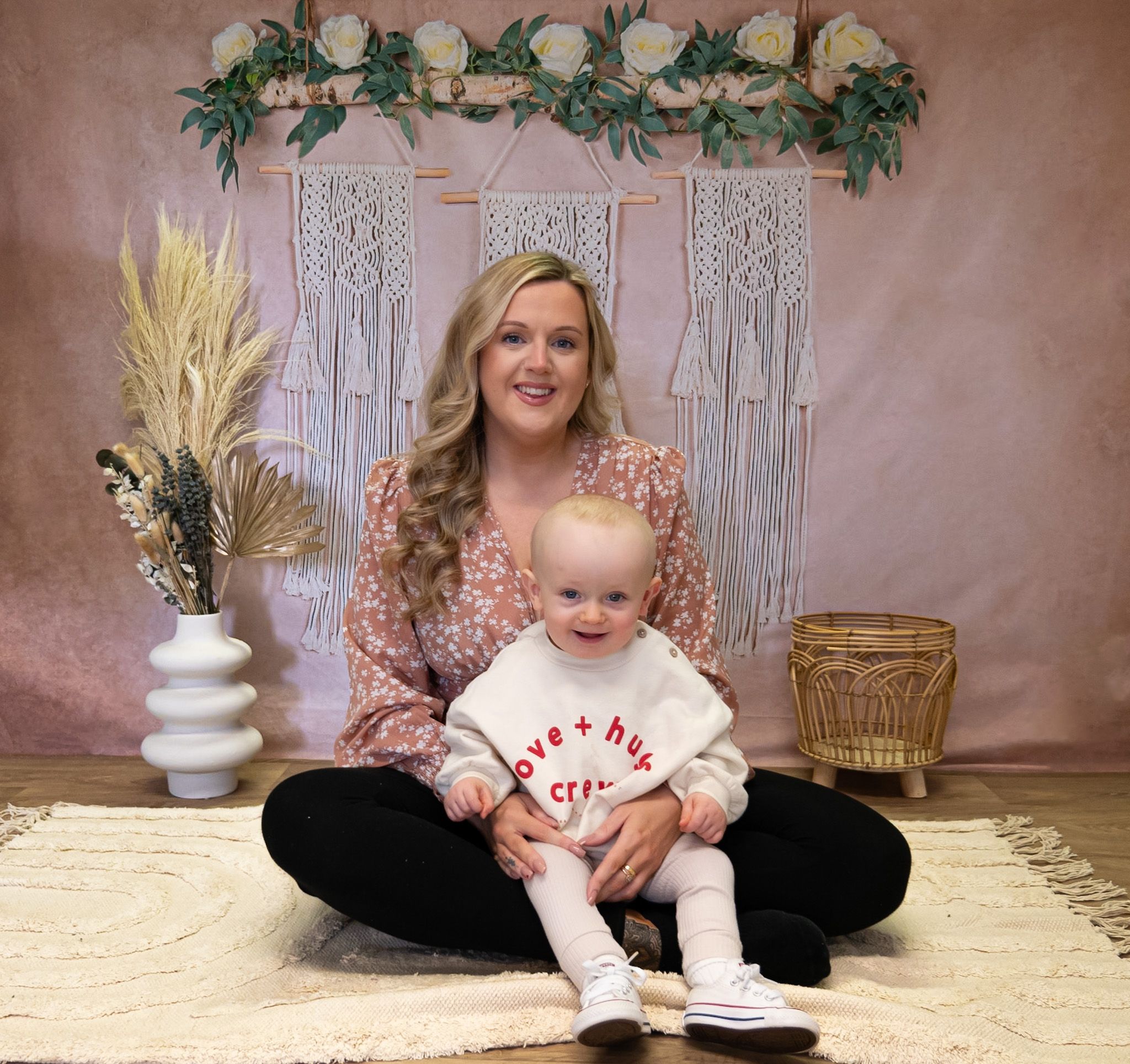 Playful interaction on a pink backdrop with decorative greenery and white accents.