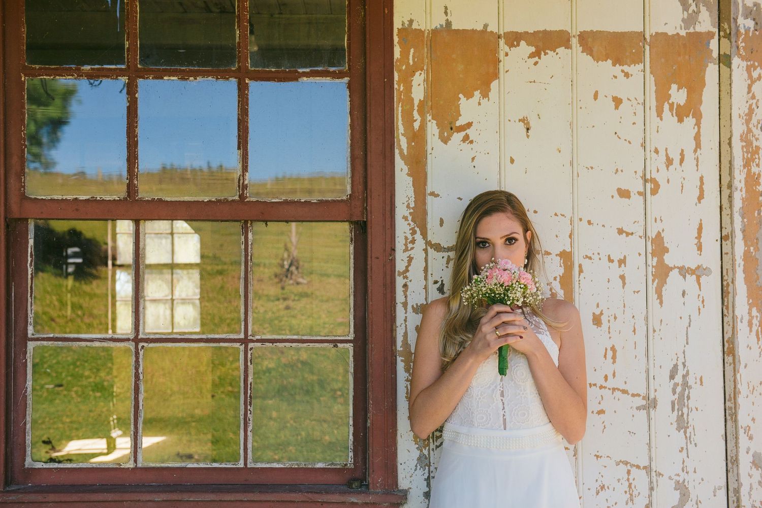 A rustic farmhouse scene with an elegant white gown contrasting against peeling paint walls.