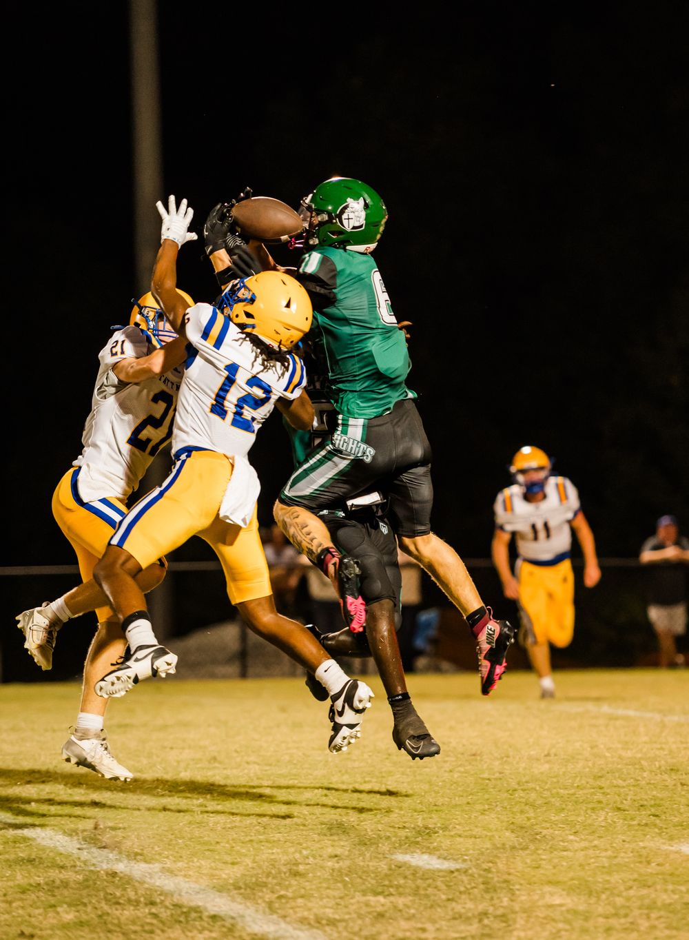 Football players collide in a dramatic tackling sequence shown across four action shots during a night game.