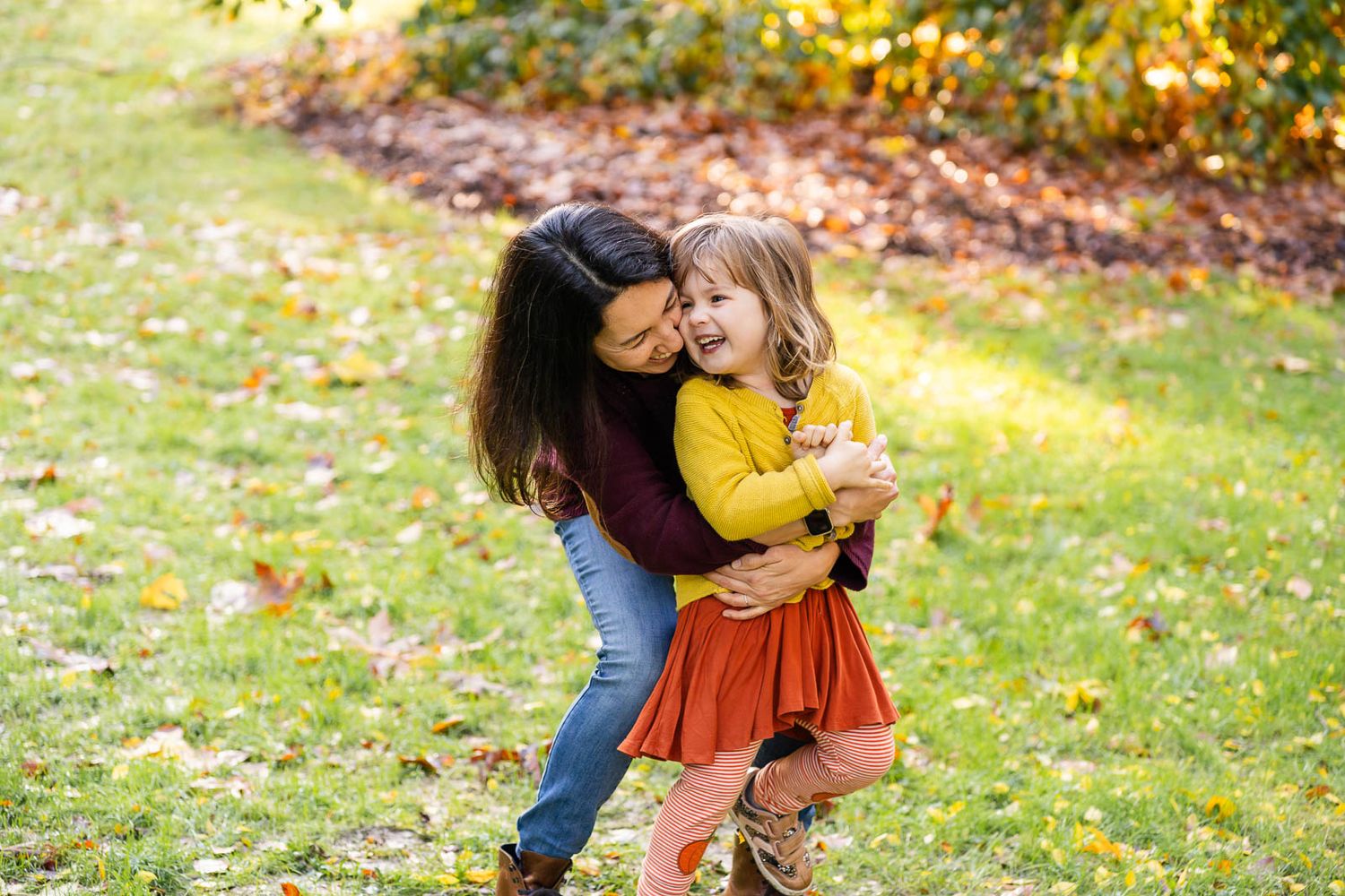 Mother hugs her laughing daughter at the Seattle Arboretum.