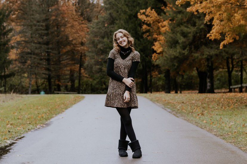 Person walking along autumn path surrounded by colorful fall foliage.
