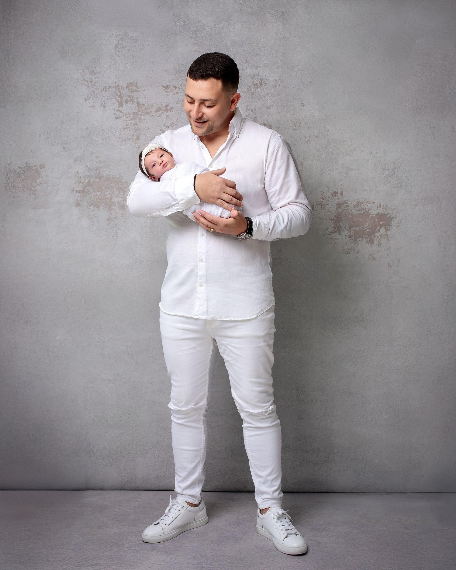 Father, daughter newborn portrait by Sydney Family Photographer Caz Captures. The dad smiling at  newborn wrapped in white, both in white.
