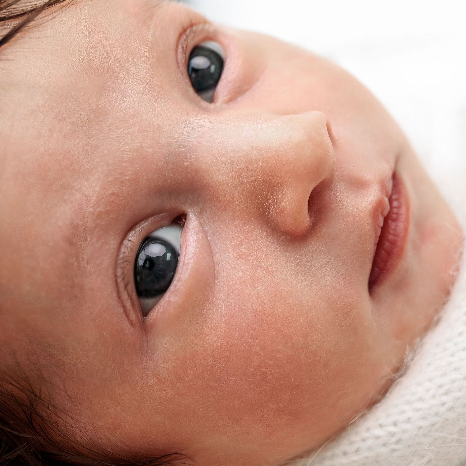 Close up newborn photos of baby girls face, wrapped in white fluffy blanket. Photography by Sydney base Newborn Photographer Caz Captures.