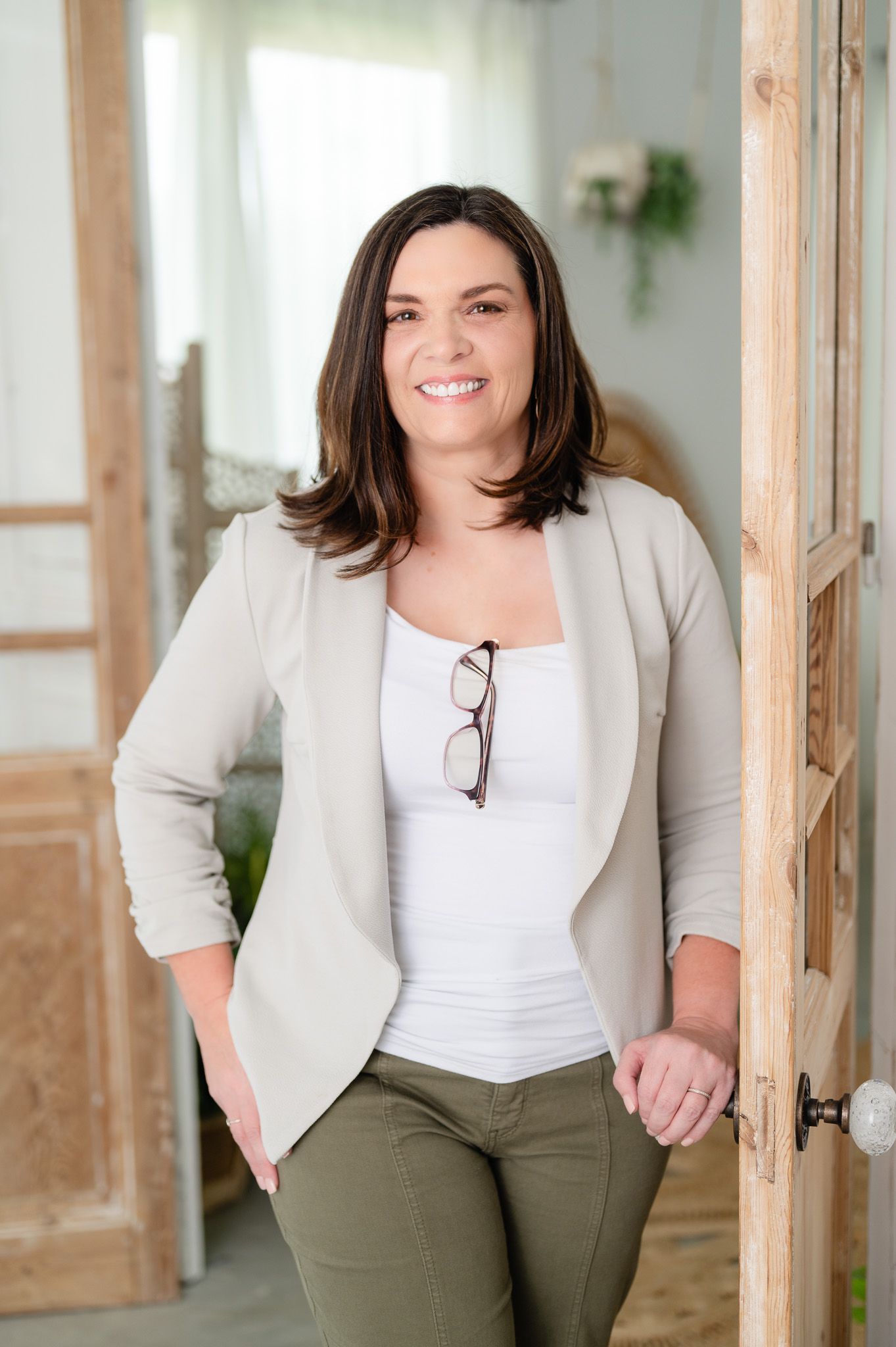 Professional portrait of healthcare worker in white coat smiling against floral backdrop.