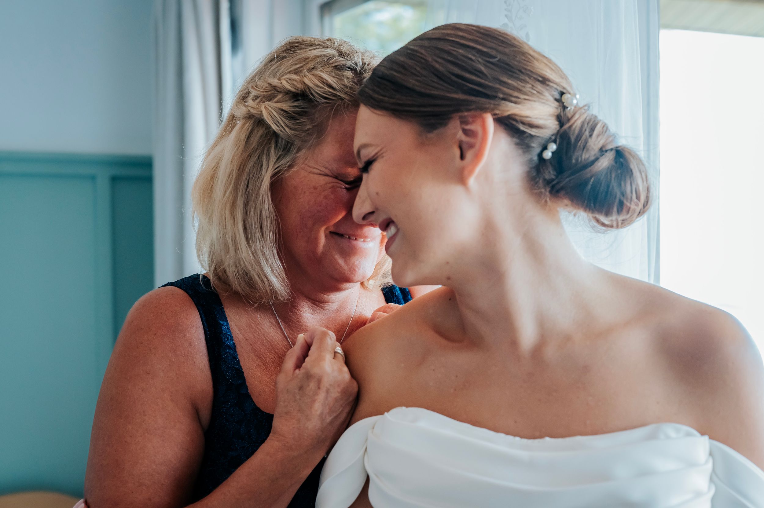 Tender moments shared during wedding preparations in a room with soft blue walls.