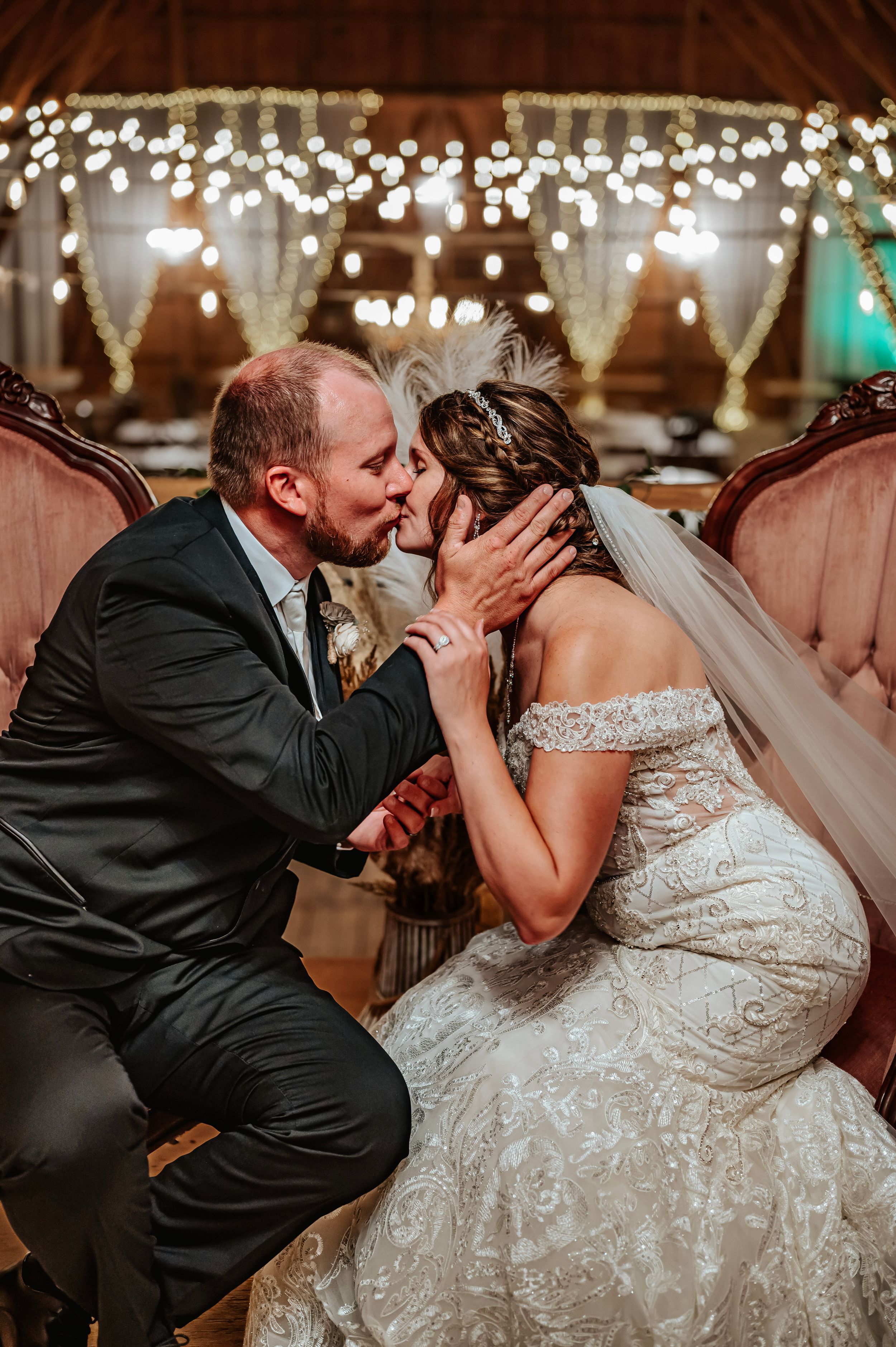 Romantic dance moment captured in rustic barn venue with twinkling lights.