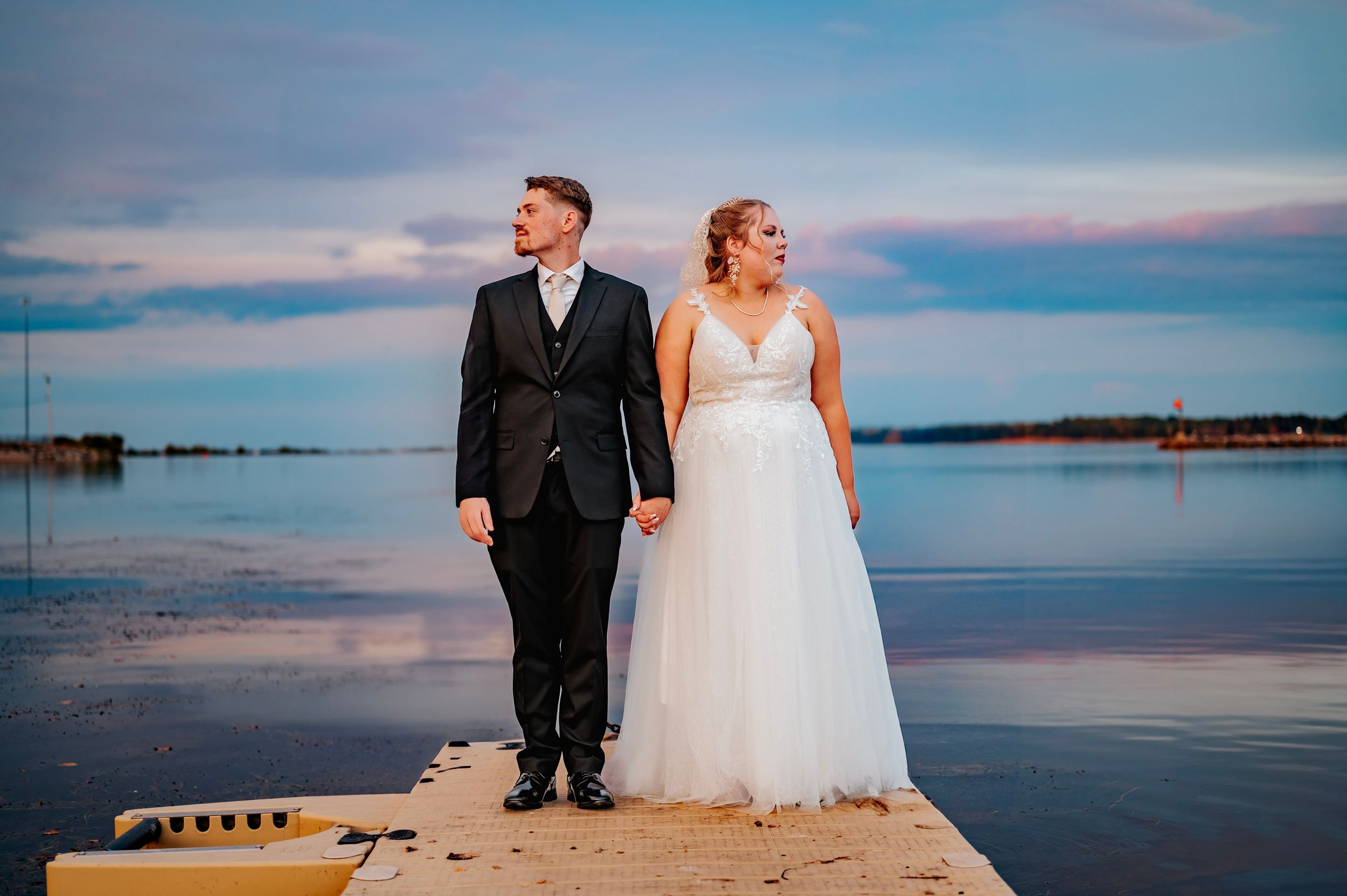 Scenic waterfront wedding photos with couple against blue sky and calm waters.