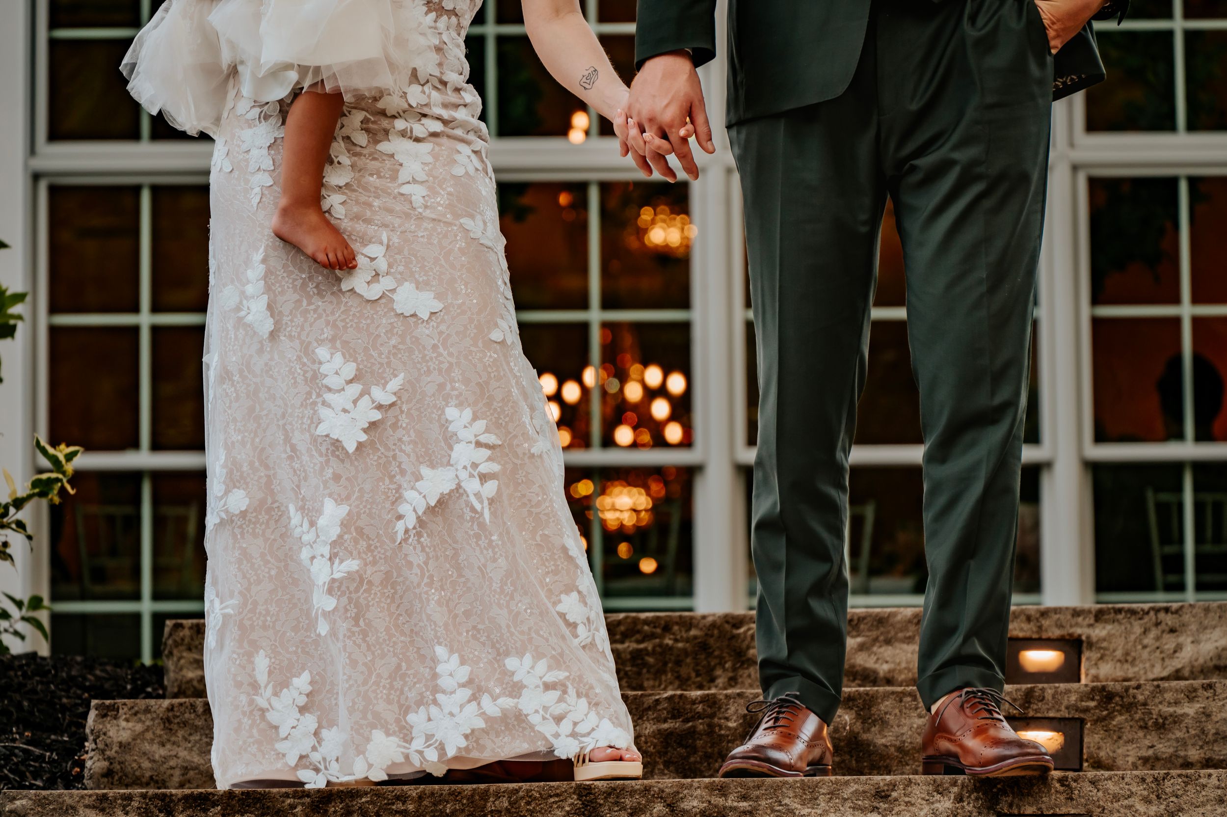 Elegant wedding couple posing on stone steps in front of white house.