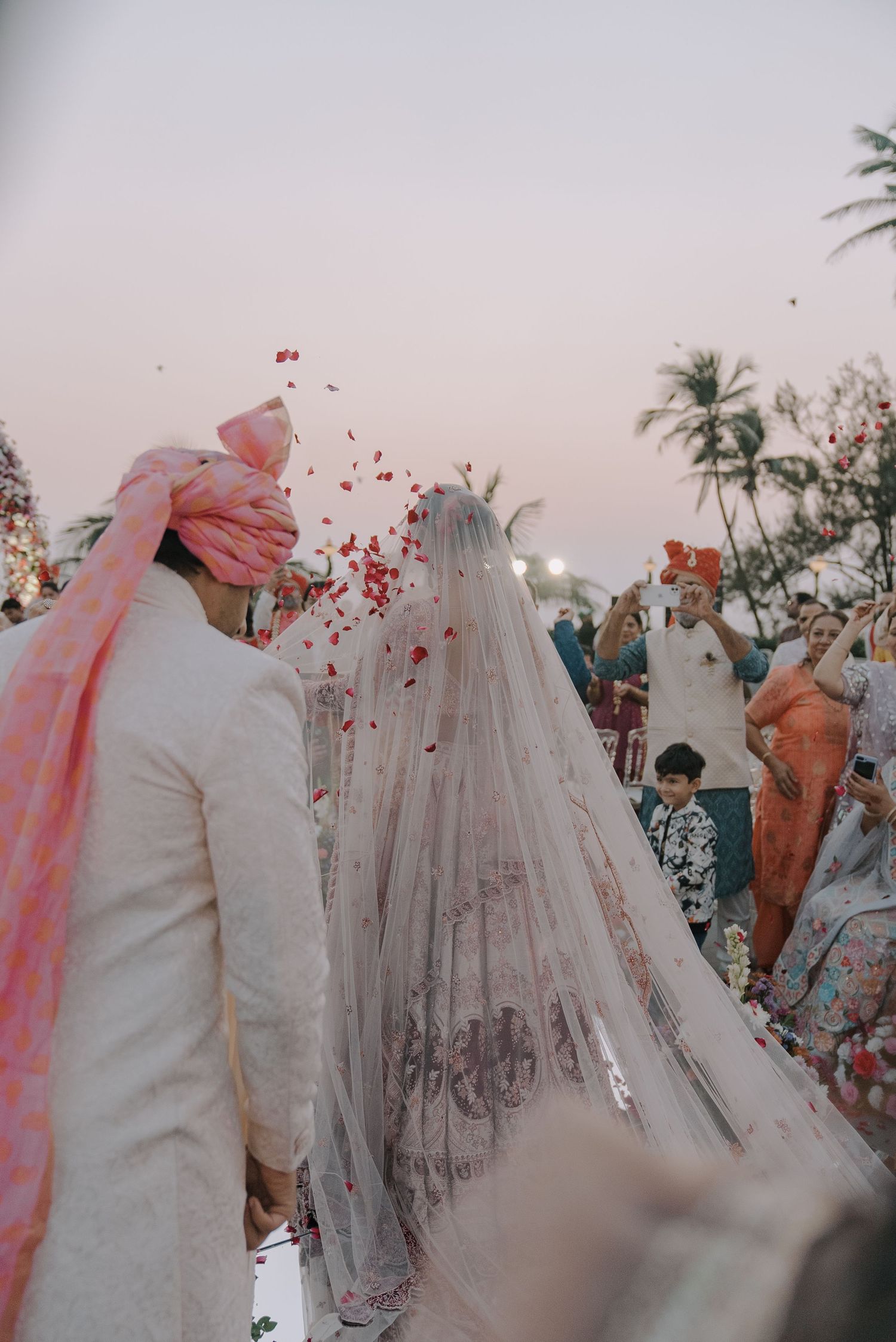Wedding celebration with rose petals being thrown over couple in outdoor setting.