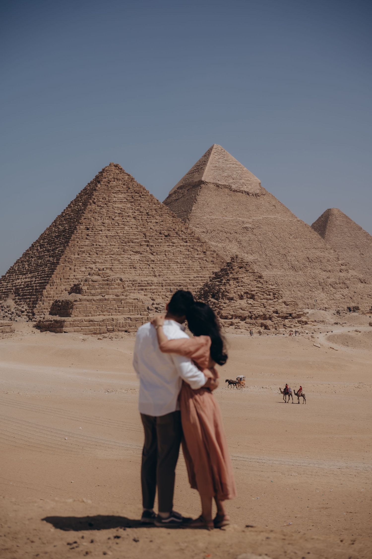 A romantic couple embraces in front of the ancient Egyptian pyramids in a series of desert landscape photos.