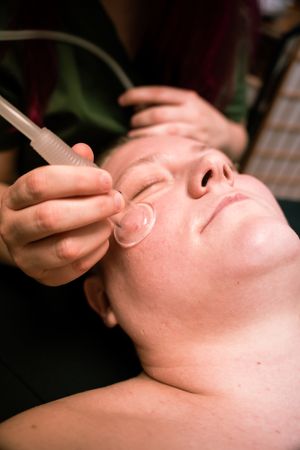 Therapeutic facial massage being performed with specialized tools in a spa setting.