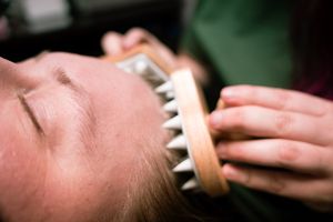 Hands applying makeup with a brush to someone's face in a professional beauty session.