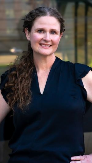 Professional portrait showing someone in dark clothing with long wavy hair.