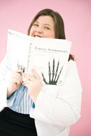 Person in blue striped shirt and lab coat holds up medical documents against pink backdrop.