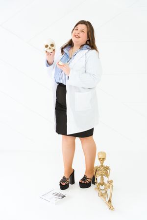 A person in a white denim jacket and black shorts poses playfully with gold decorative objects against a white background.